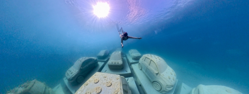 Diver underwater with car sculptures. Photo by Brittany Weber.