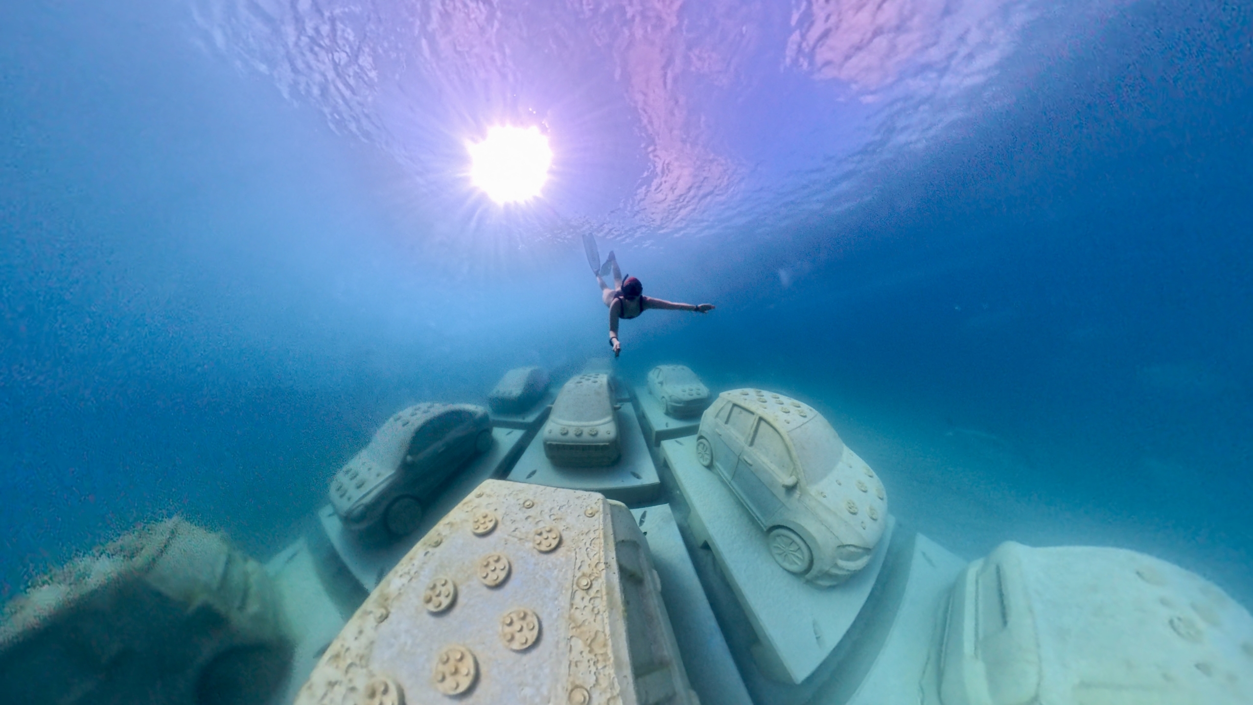 Diver underwater with car sculptures. Photo by Brittany Weber.